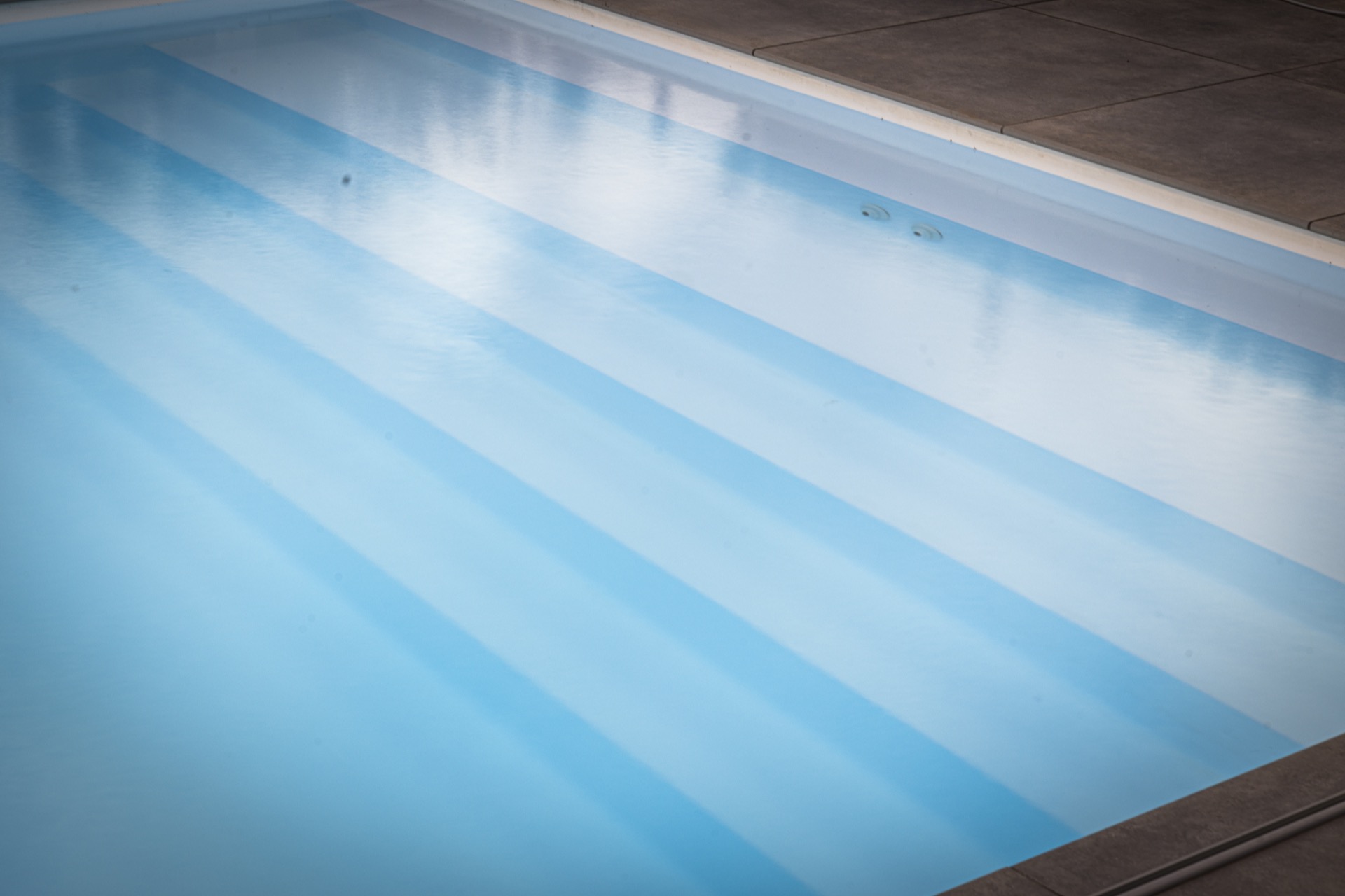 piscina rettangolare moderna con scala d’ingresso larga e zona lounge: primo piano dell’acqua limpida della piscina con, Luxury, Design, Exclusive, Modern, Custom Made, Special, Beautiful