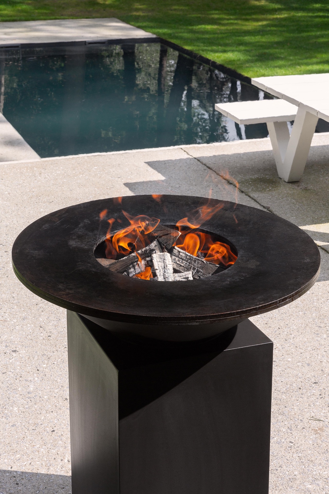 giardino moderno con braciere rotondo e area con acqua: primo piano di un braciere rotondo con fiamme vicino a uno specchio, Luxury, Design, Exclusive, Modern, Custom Made, Special, Beautiful