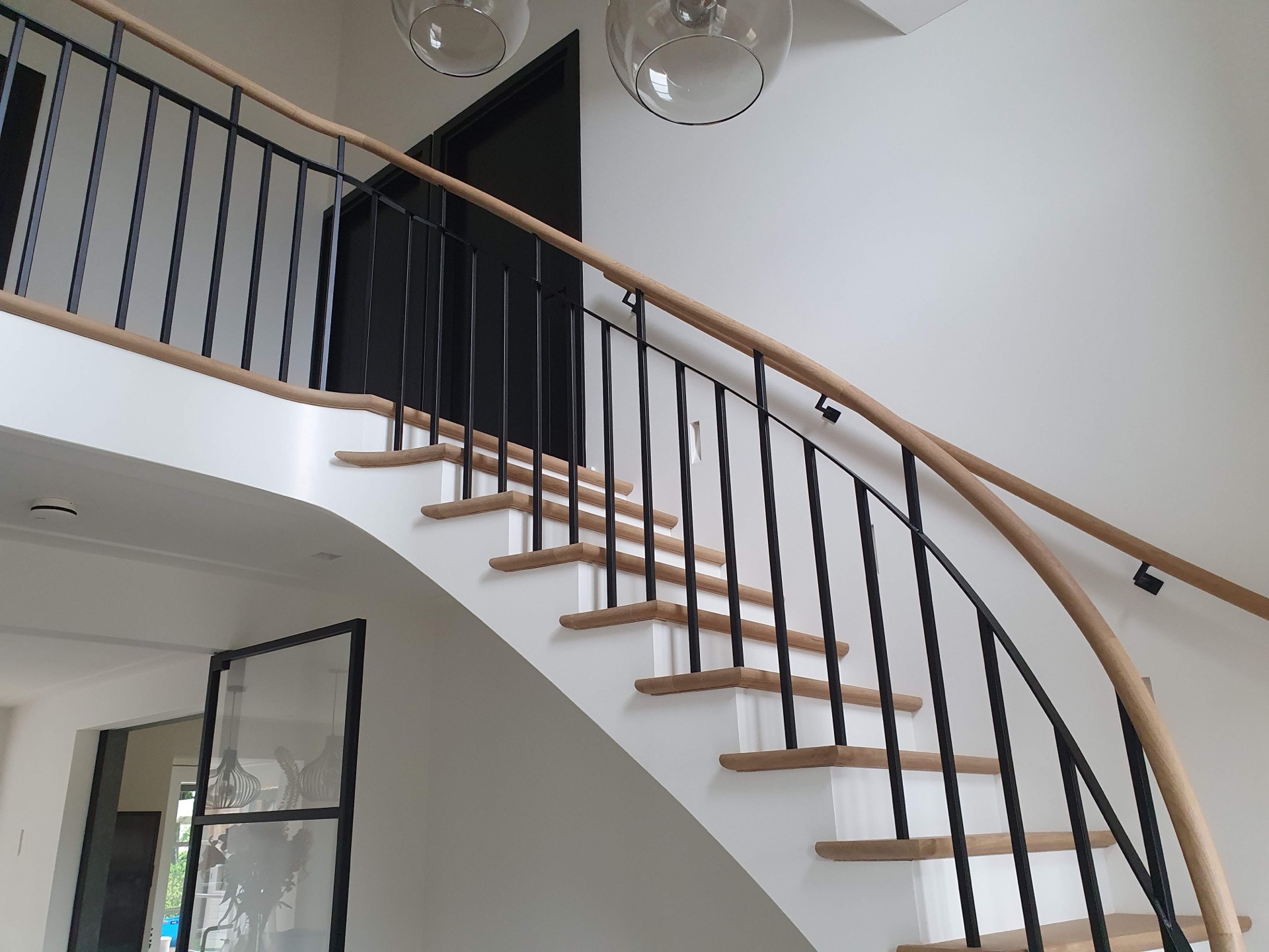 scala a un quarto di giro con ringhiera: vista della scala di sbieco: corrimano in legno, balaustre nere e alzate bianche, Luxury, Design, Exclusive, Modern, Custom Made, Special, Beautiful