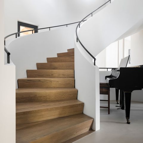 Curved staircase with wooden steps and black handrail