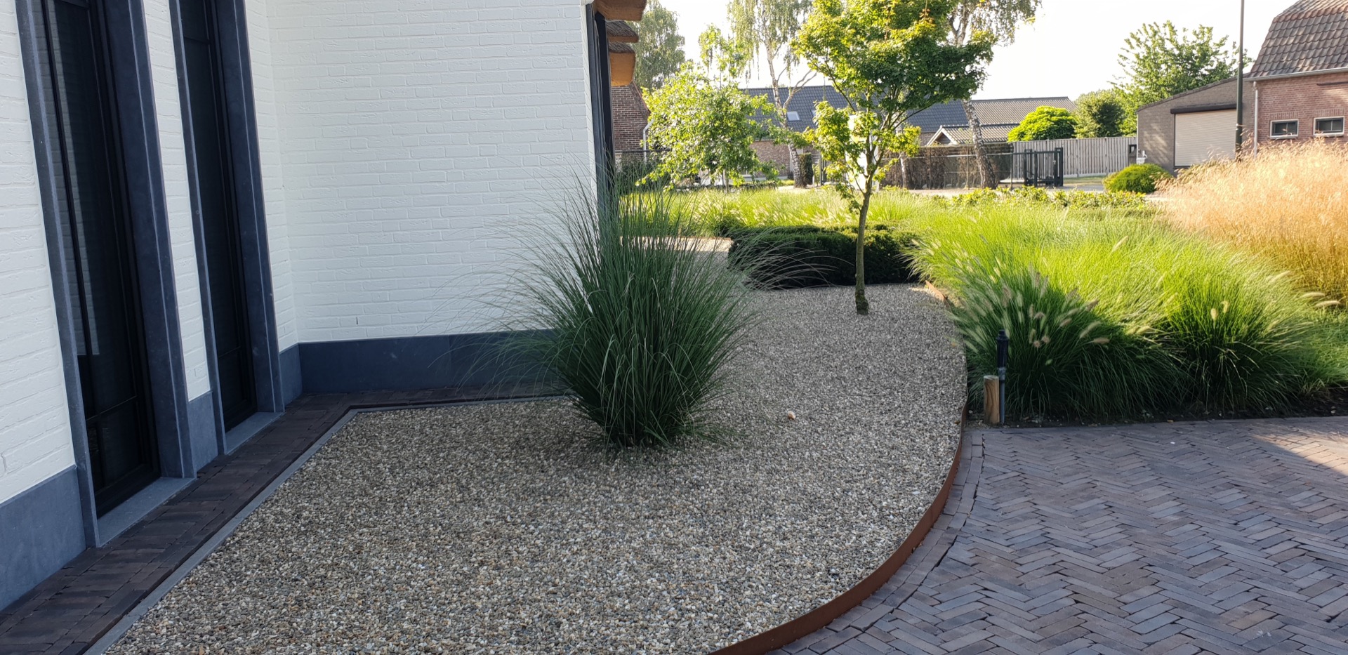 giardino con forme organiche per una casa di campagna: aiia in ghiaia con graminacee ornamentali lungo una facciata bianca e, Luxury, Design, Exclusive, Modern, Custom Made, Special, Beautiful