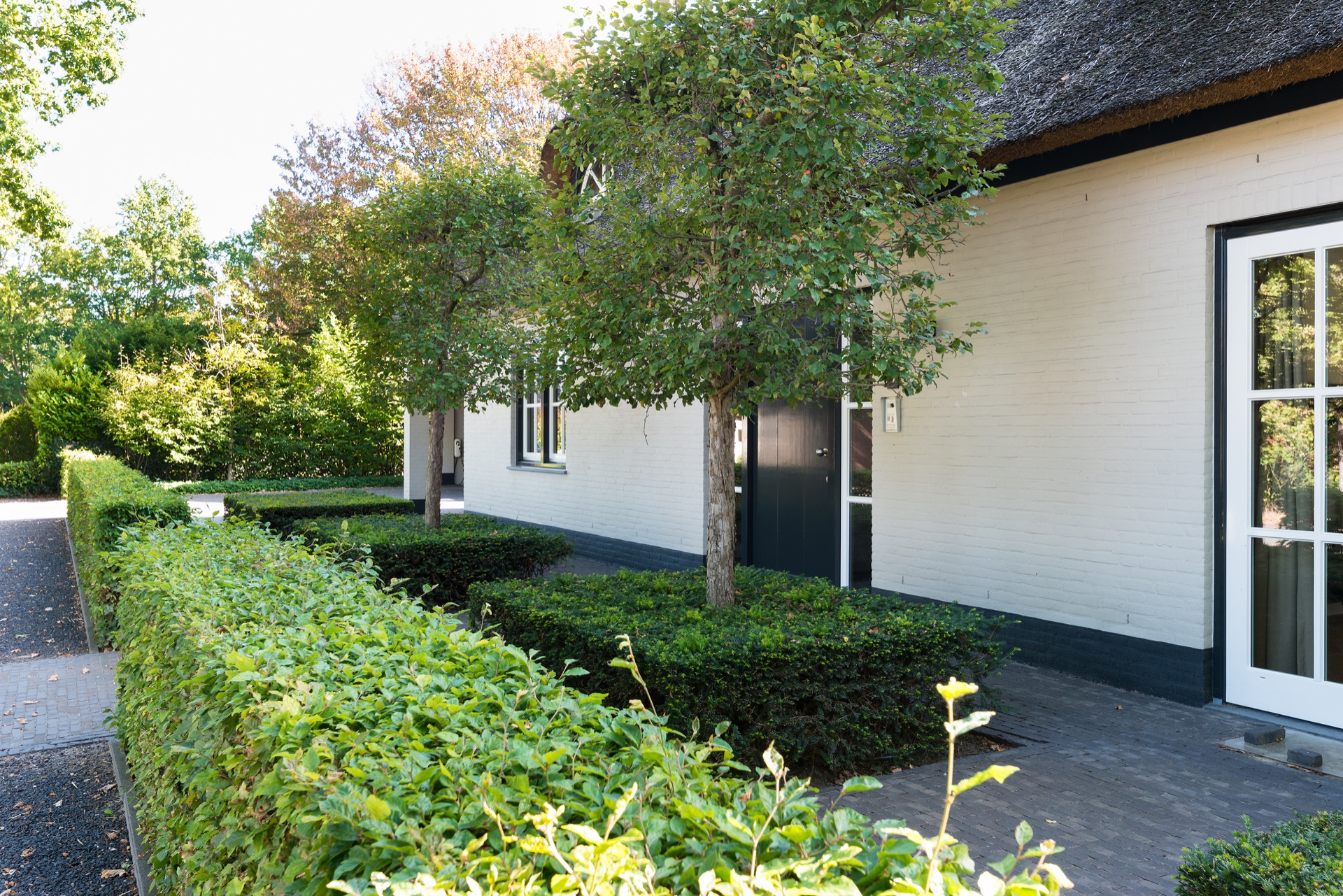 giardino di campagna con aree giardino: facciata bianca della casa con finestre e siepi lungo un sentiero pavimentato, Luxe, Design, Exclusief, Modern, Maatwerk, Bijzondere, Mooie