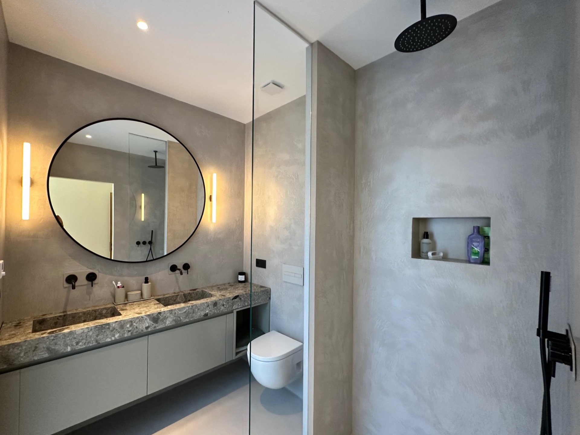 finitura microtopping continua in una casa moderna: area doccia in bagno con divisorio in vetro, specchio rotondo e texture, Luxury, Design, Exclusive, Modern, Custom Made, Special, Beautiful