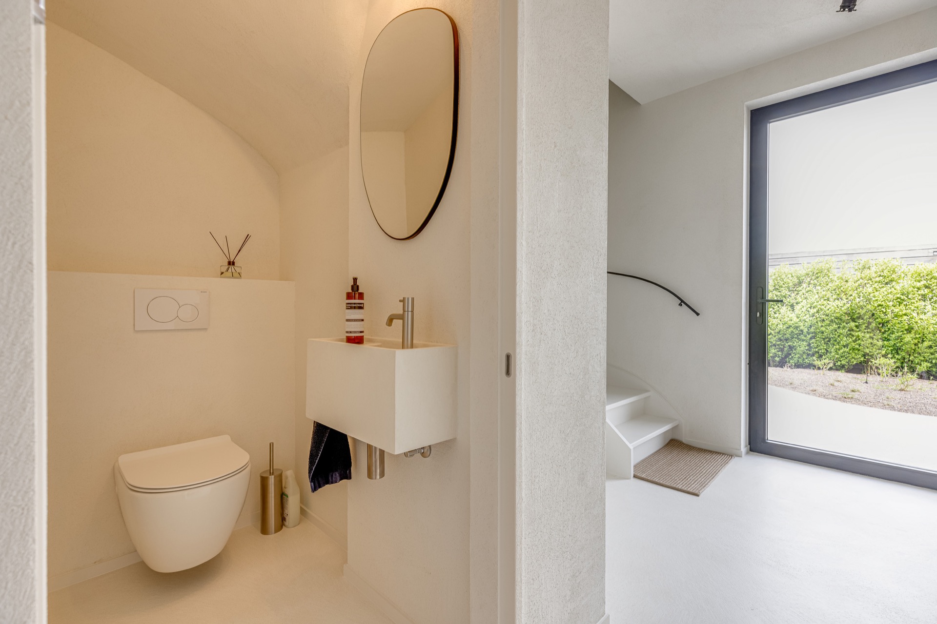 finitura opaca continua in microtopping: area WC con lavabo incassato, specchio rotondo e finestra accanto alla nicchia, Luxury, Design, Exclusive, Modern, Custom Made, Special, Beautiful