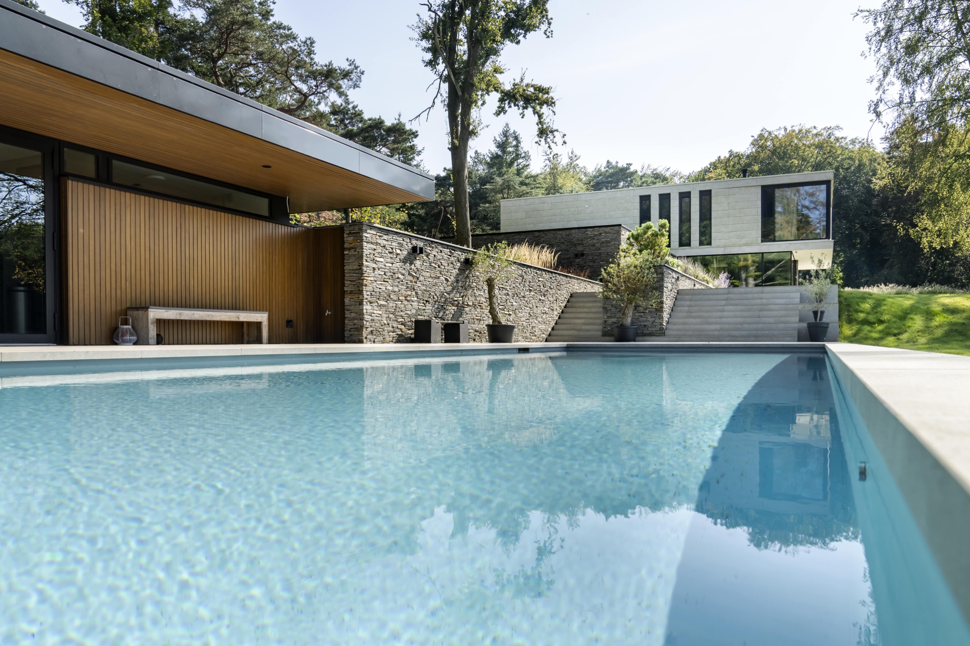 piscina skimmer rivestimento grigio chiaro: primo piano dell’acqua della piscina con vista su muro in pietra naturale e, Luxury, Design, Exclusive, Modern, Custom Made, Special, Beautiful