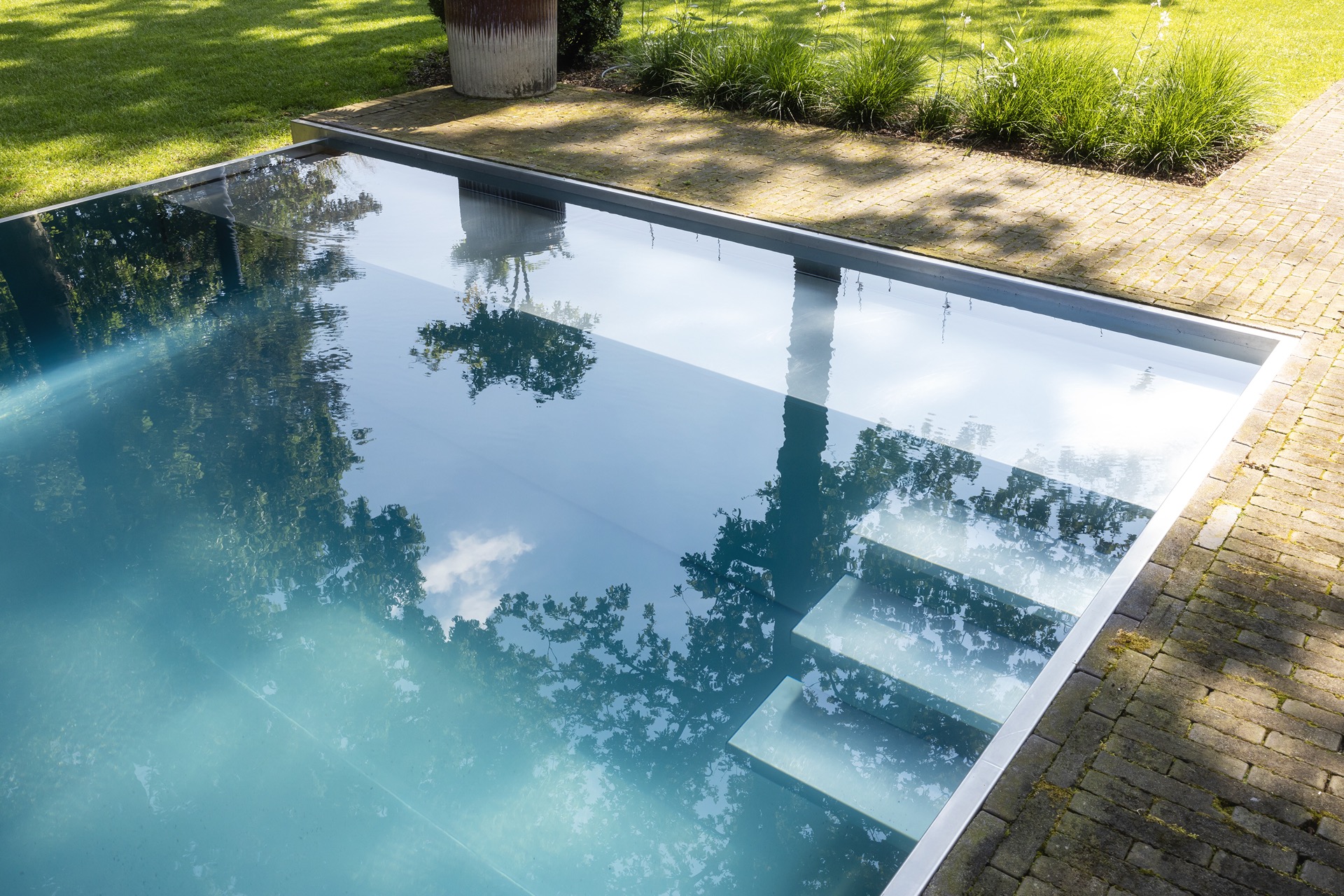 piscina rettangolare moderna: primo piano dell’acqua blu della piscina con riflessi degli alberi e linea di bordo pulita, Luxury, Design, Exclusive, Modern, Custom Made, Special, Beautiful