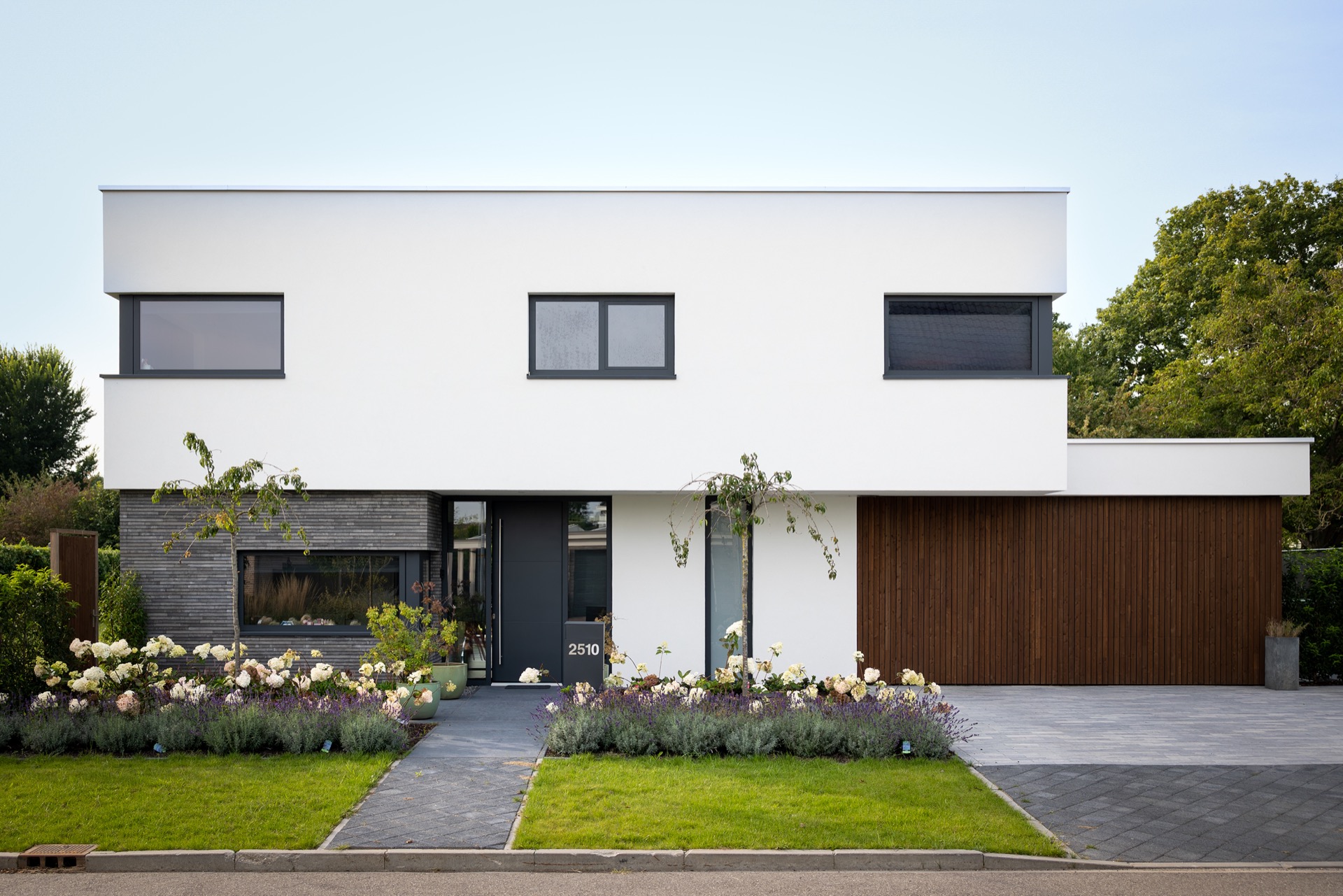 ristrutturazione casa: villa moderna con facciata bianca, infissi scuri e portone garage in legno sul vialetto, Luxe, Design, Exclusief, Modern, Maatwerk, Bijzondere, Mooie