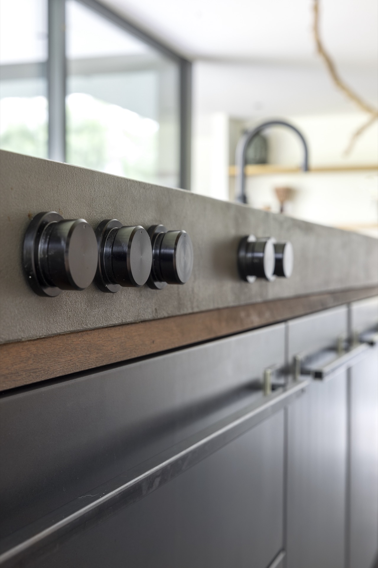country kitchen with island: close-up of knobs/handles on lower cabinets near a grey countertop and faucet in a country, Luxury, Design, Exclusive, Modern, Custom Made, Special, Beautiful