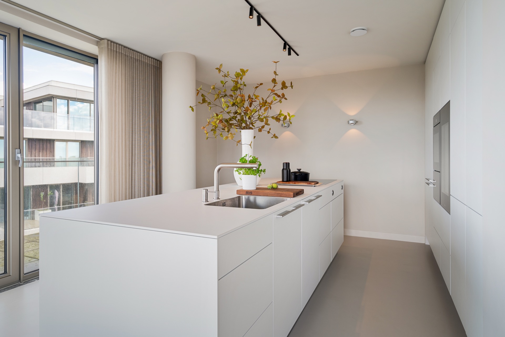 modern new-build kitchen island: modern open-plan kitchen with white island, sink area and track lighting by large windows, Luxe, Design, Exclusief, Modern, Maatwerk, Bijzondere, Mooie