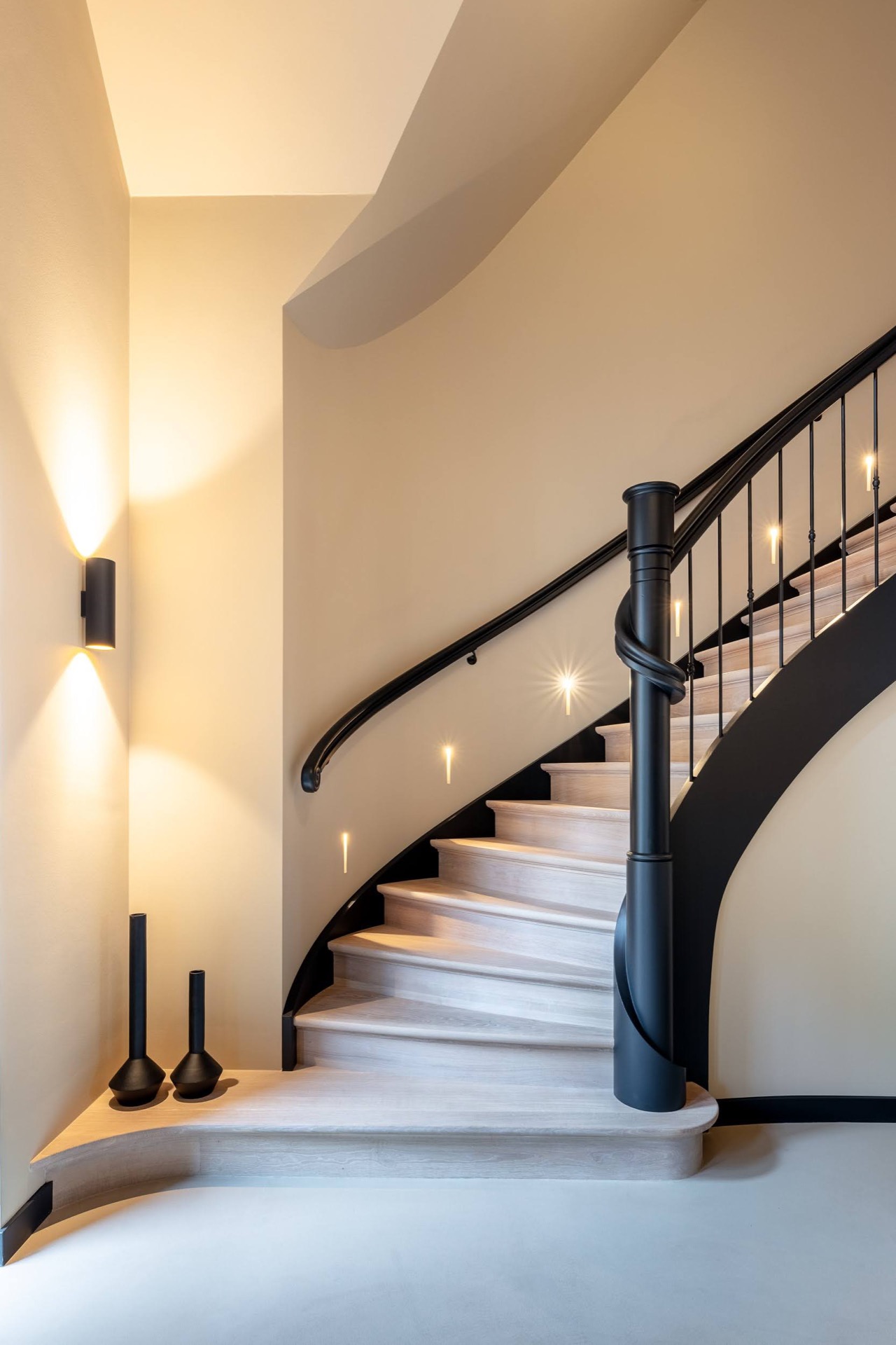 scala curva a quarto di giro: primo piano della ringhiera curva in ferro battuto e della parete della scala illuminata, Luxury, Design, Exclusive, Modern, Custom Made, Special, Beautiful