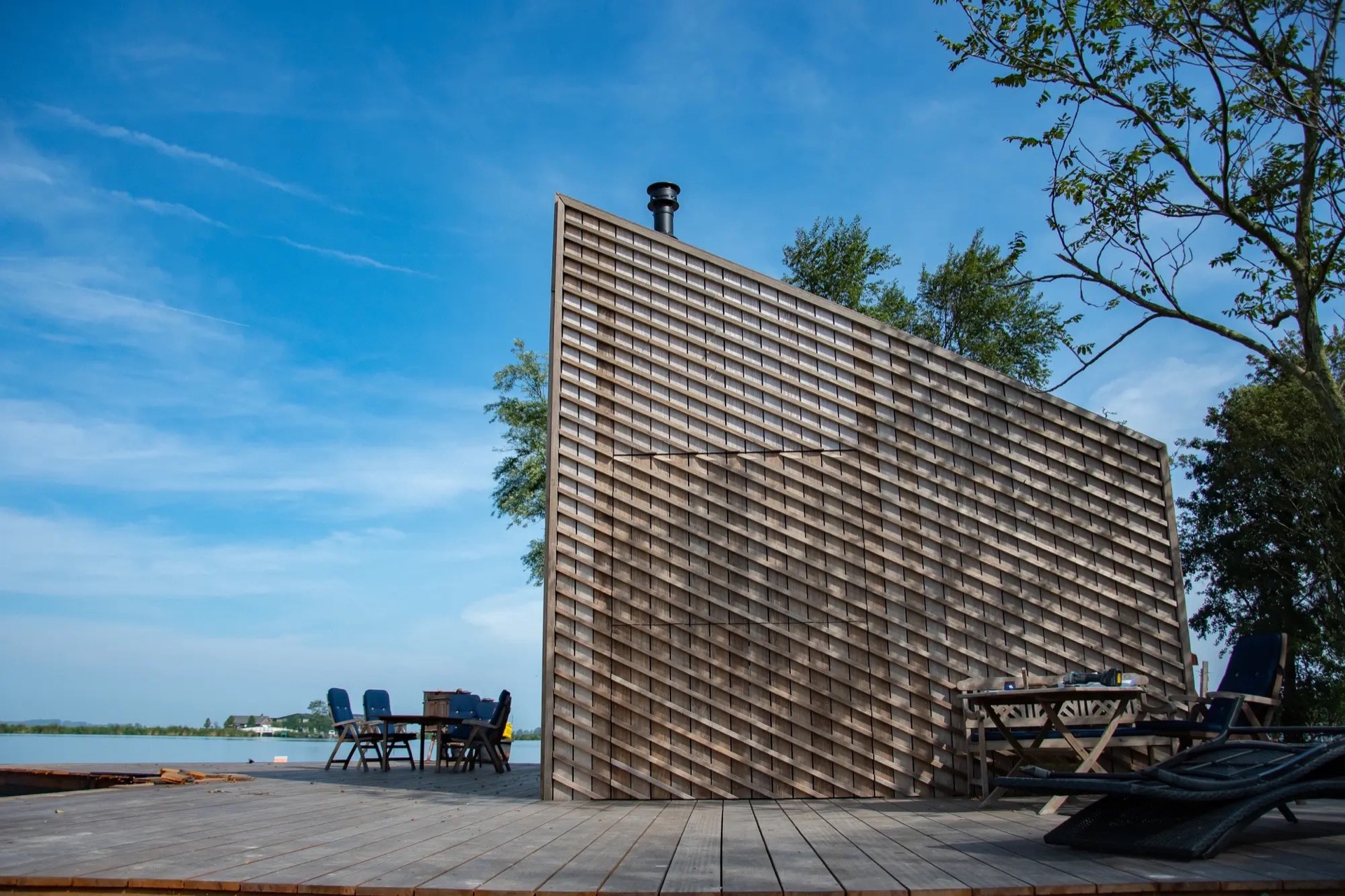 rivestimento in legno per pareti: facciata in legno con persiane pieghevoli e mobili da giardino sotto cielo azzurro., Luxury, Design, Exclusive, Modern, Custom Made, Special, Beautiful