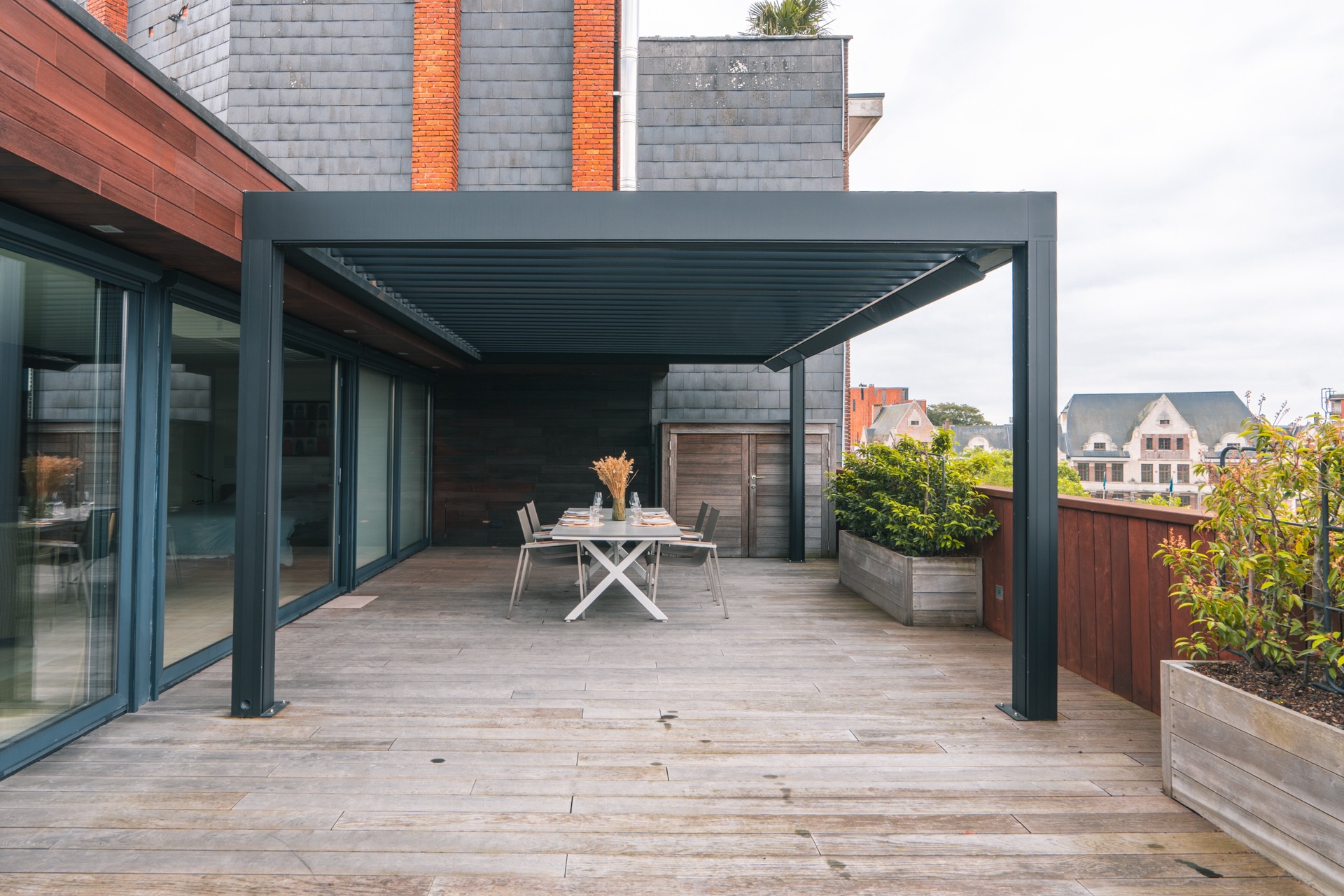 Terrazza sul tetto di lusso con tetto a lamelle: tavolo con decorazione su terrazza con mobili in legno e vasi di fiori, Luxury, Design, Exclusive, Modern, Custom Made, Special, Beautiful