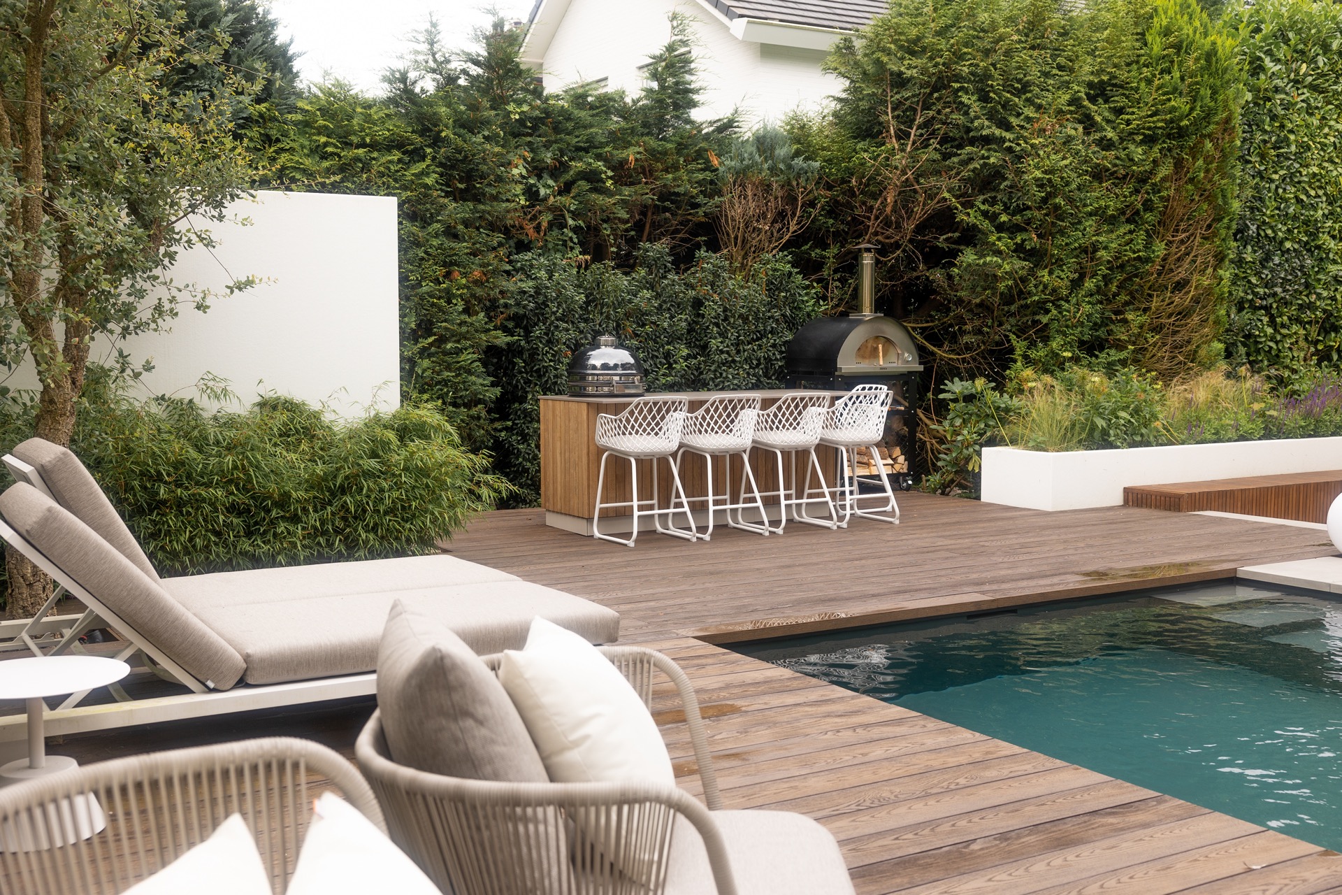 cucina esterna legno: cucina esterna con sgabelli bianchi su terrazza in legno vicino a piscina e giardino verde, Luxury, Design, Exclusive, Modern, Custom Made, Special, Beautiful