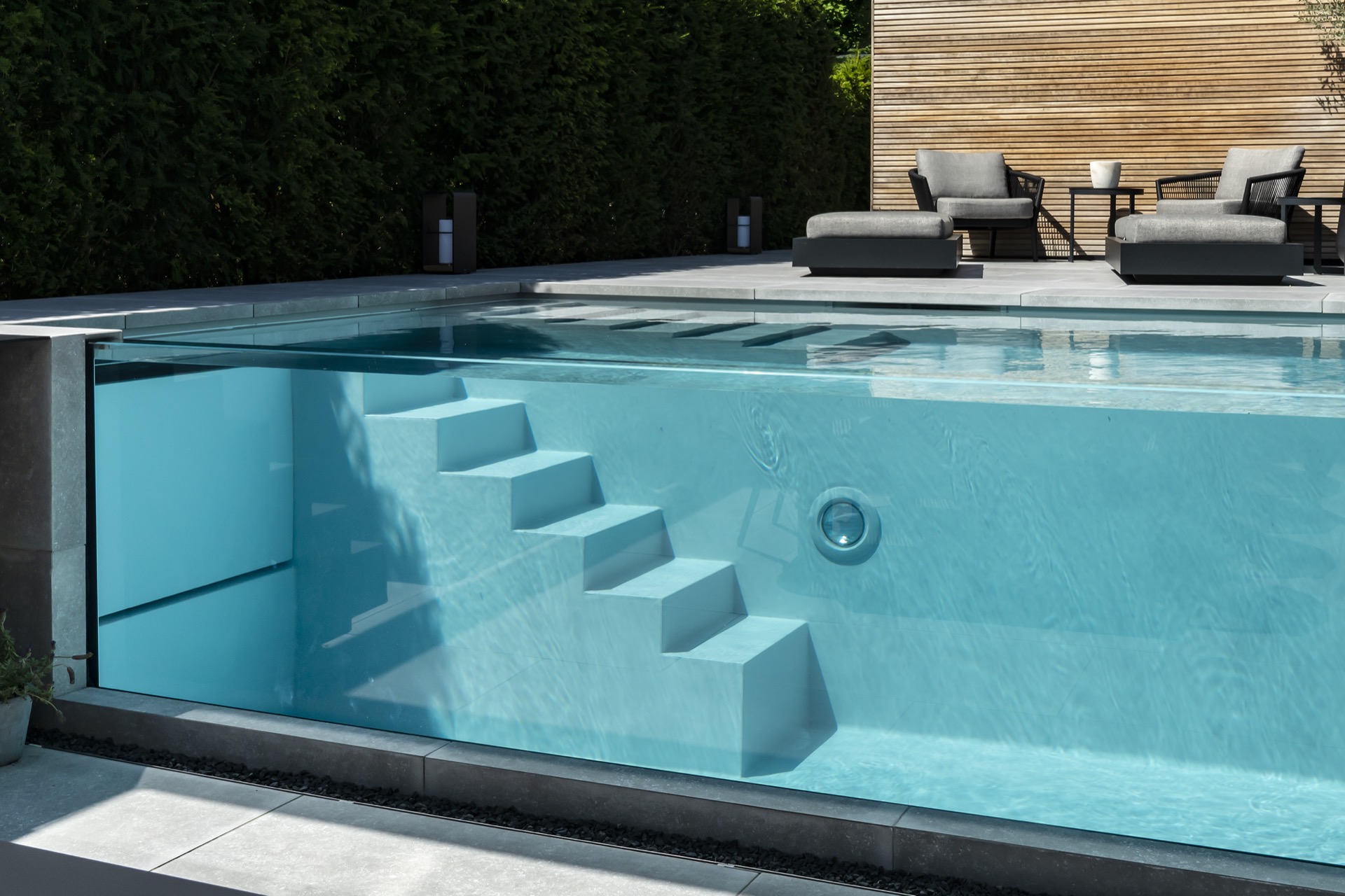 piscina con parete in vetro: primo piano parete piscina in vetro con bordo in cemento e riflesso sull'acqua, Luxury, Design, Exclusive, Modern, Custom Made, Special, Beautiful