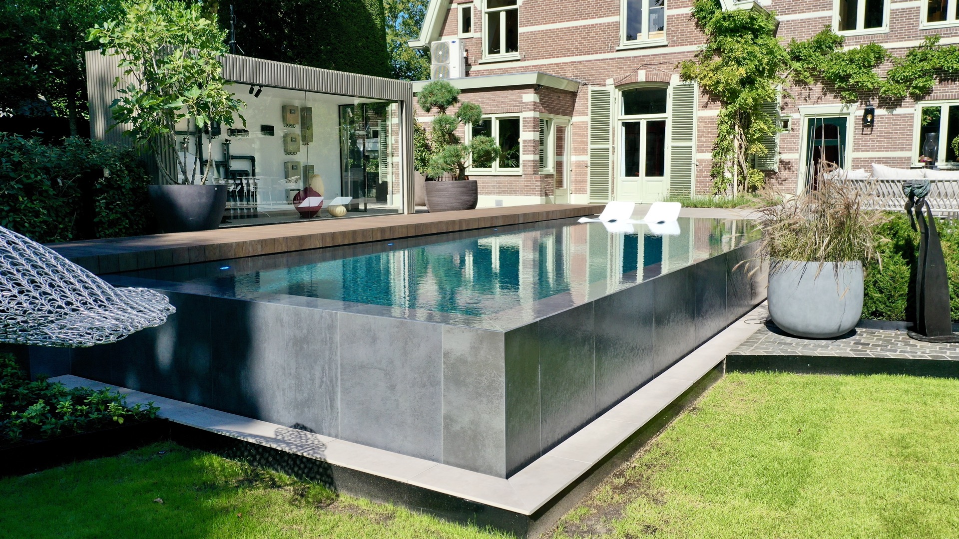 locale tecnico piscina fuori terra: vista laterale piscina rialzata effetto cemento vicino casa classica con persiane verdi, Luxury, Design, Exclusive, Modern, Custom Made, Special, Beautiful