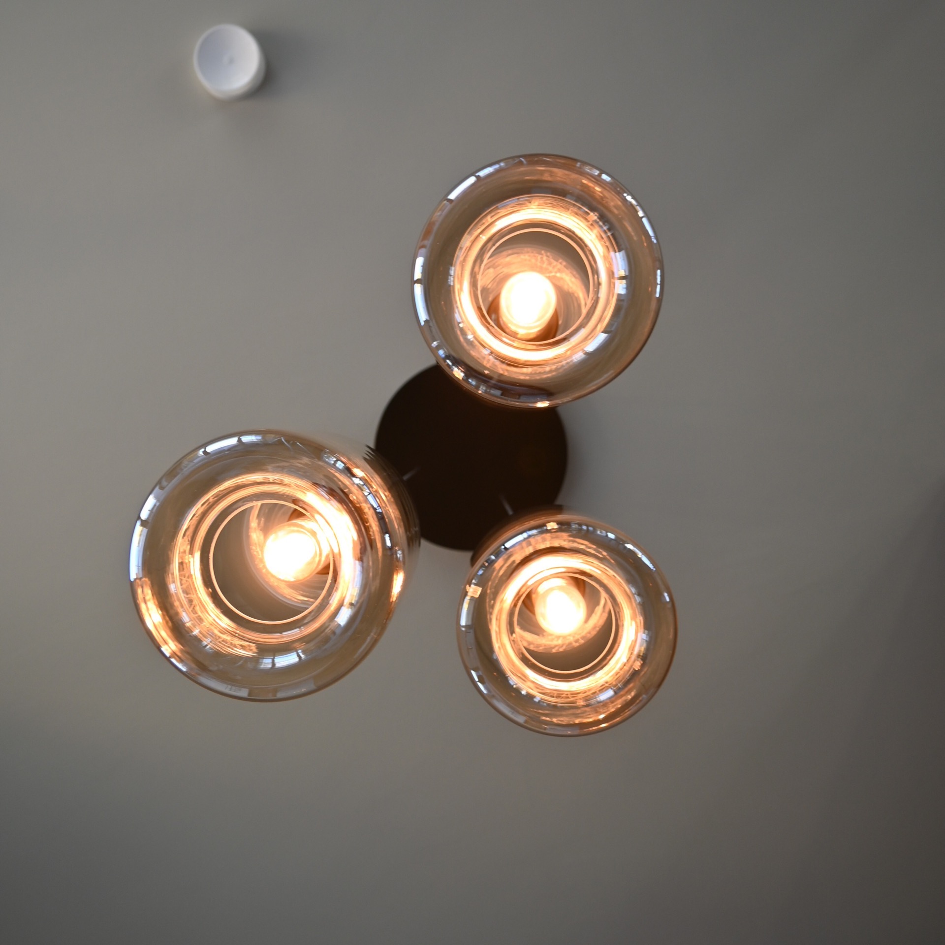rivestimento in legno per pareti: tre lampade a sospensione cilindriche in vetro viste dal basso con luce calda, Luxury, Design, Exclusive, Modern, Custom Made, Special, Beautiful